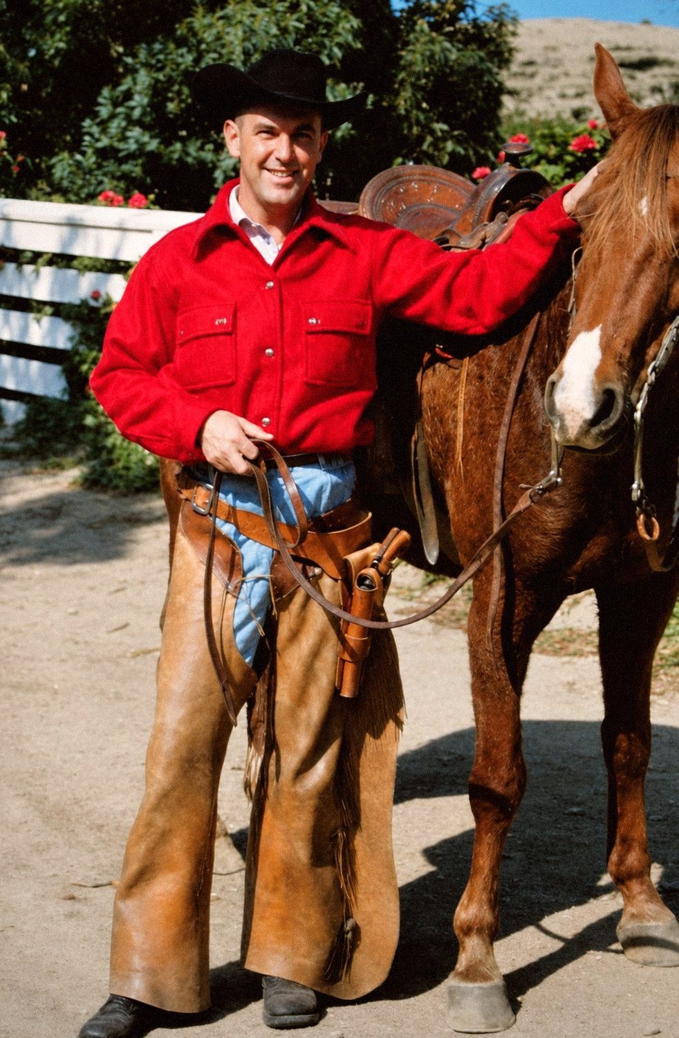 Jack Blacker in ranch gear beside his saddled horse